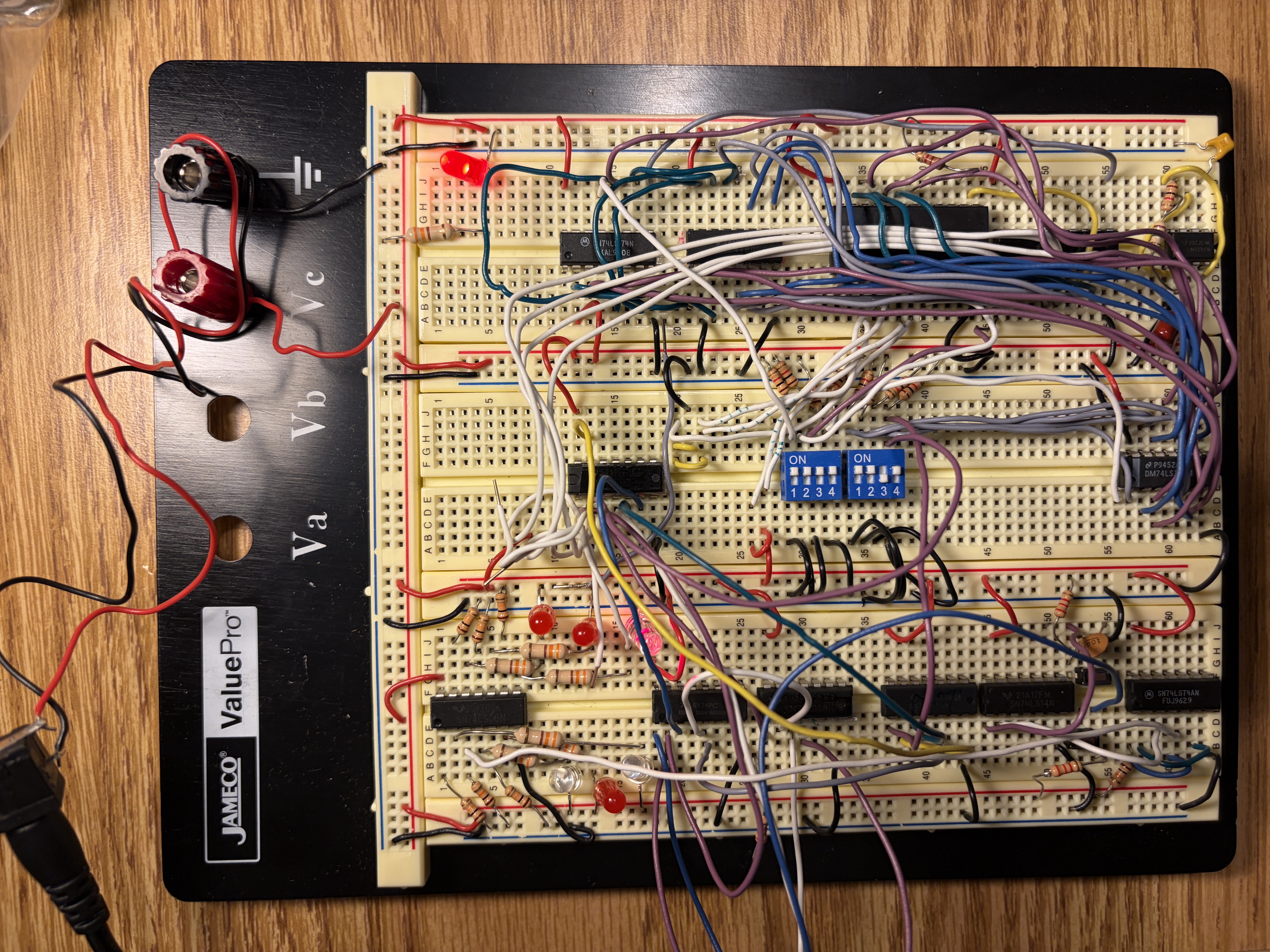 Completed 4-bit processor built across a large breadboard: multiple TTL chips, ROMs, DIP switches, LEDs, and a dense web of jumper wires
