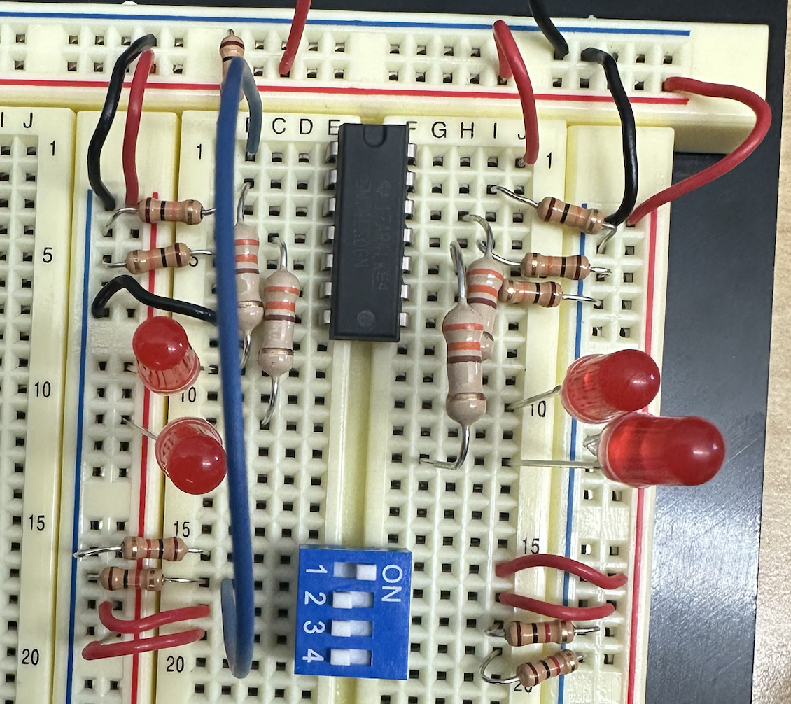 Breadboard with an inverter chip, current-limiting resistors, LEDs, and a DIP switch bank